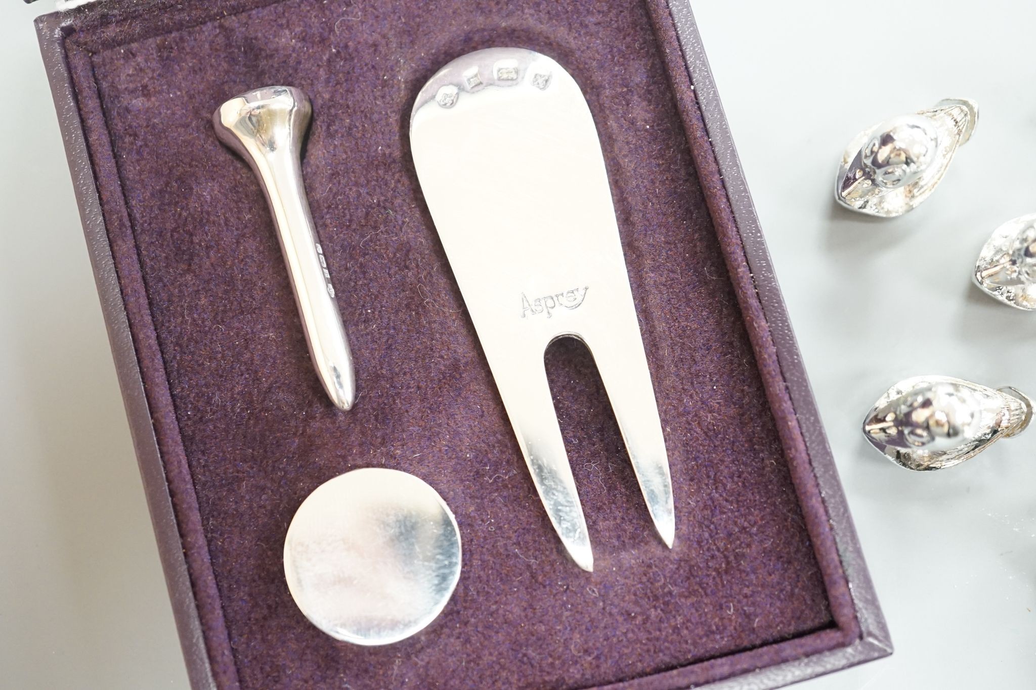 A modern Asprey cased silver golfer's companion set, comprising a tee, marker and pitch mark repairer, together with a set of six metal duck menu holders.